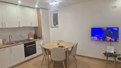 a kitchen with a table and a tv on the wall at Bella Vacanza Apartment in Banja Luka