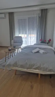 a bedroom with a large bed and a chair at Bella Vacanza Apartment in Banja Luka