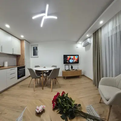 a living room with a dining table and a kitchen at Bella Vacanza Apartment in Banja Luka