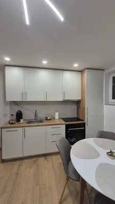 a kitchen with white cabinets and a table at Bella Vacanza Apartment in Banja Luka