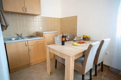a kitchen with a wooden table with chairs and a bottle of wine at Apartmani Biser Kupresa 1 in Kupres