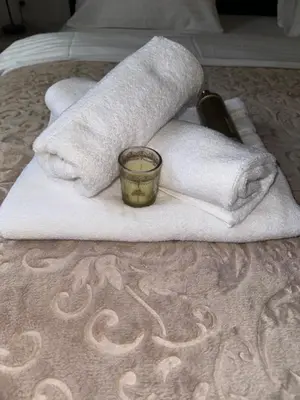a pile of towels and a candle on a bed at Country House Lištani-renta quad in Livno