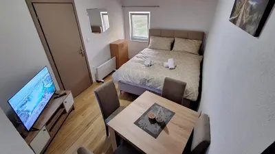 a small room with a bed and a table and a television at Apartman Biser Kupresa 3 in Kupres