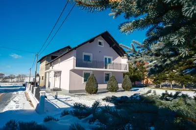a white house with a balcony and trees at Apartman Biser Kupresa 3 in Kupres