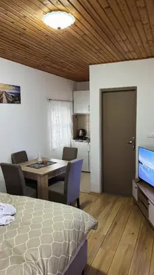 a room with a bed and a table and a kitchen at Apartman Biser Kupresa 3 in Kupres