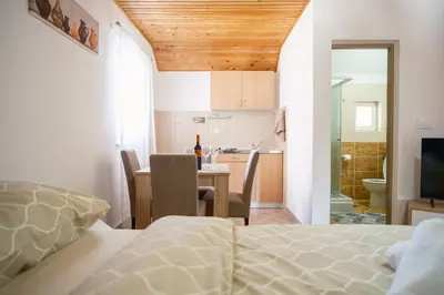 a bedroom with a bed and a table and a kitchen at Apartmani Biser Kupresa 4 in Kupres