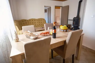 a dining room table with a bottle of wine and fruit at Apartmani Biser Kupresa 5 in Kupres