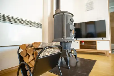 a living room with a wood stove and a chair at Apartmani Biser Kupresa 5 in Kupres