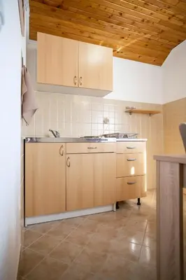 a kitchen with wooden cabinets and a sink at Apartmani Biser Kupresa 5 in Kupres