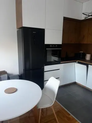 a kitchen with a white table and a black refrigerator at Apartman Sofija Banja Luka in Banja Luka