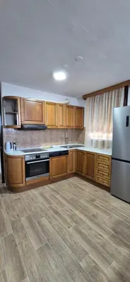 a large kitchen with wooden cabinets and a refrigerator at Center Heritage Apartment in Teslić