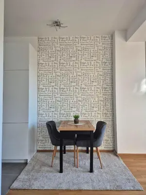 a table and chairs in a room with a wall at Apartman Sto in Banja Luka