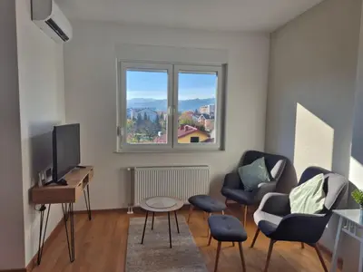 a living room with a tv and chairs and a window at Apartman Sto in Banja Luka