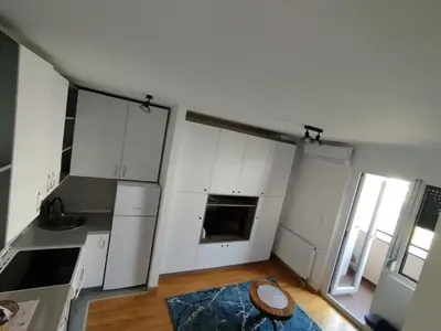 a kitchen with white cabinets and a wooden floor at Apartman Dunja Doboj in Doboj