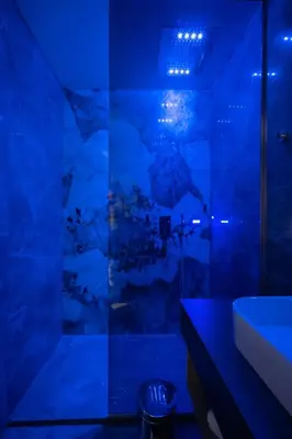 a blue bathroom with a shower and a sink at Luxury Apartments Palata - Stan Infinity in Banja Luka