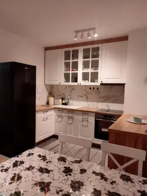 a kitchen with white cabinets and a black refrigerator at Apartman Panić in Bosanska Gradiška