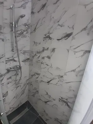 a bathroom with a shower with white marble walls at stan san banjaluka in Banja Luka
