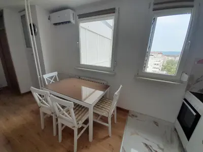 a dining room with a table and chairs and two windows at stan san banjaluka in Banja Luka