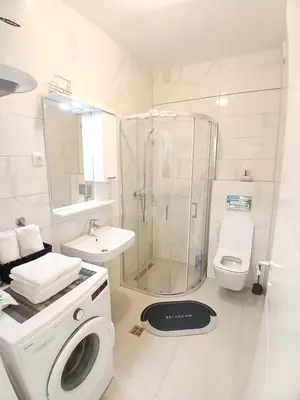 a white bathroom with a shower and a washing machine at Silencio in Banja Luka