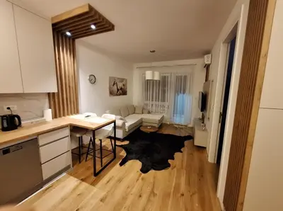 a kitchen and a living room with a table at Stan na dan Trn Laktasi Apartman Andrea in Trn