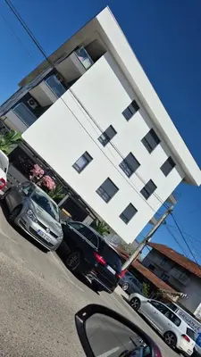 a large white building with cars parked in front of it at Stan na dan Trn Laktasi Apartman Andrea in Trn