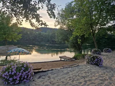 a picnic table and an umbrella next to a lake at Kuća za odmor 