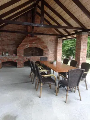 a wooden table and chairs with a brick fireplace at Vikendica Šššuma in Srbac
