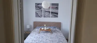 a bedroom with a bed with a table and two pictures at Vikendica Šššuma in Srbac