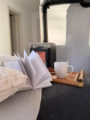 a person reading a book next to a tray with a coffee cup at Vikendica Šššuma in Srbac