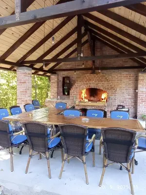 a large wooden table and chairs in front of a brick fireplace at Vikendica Šššuma in Srbac