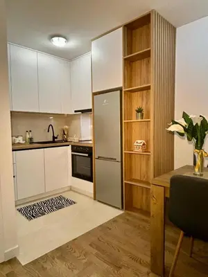 a kitchen with white cabinets and a refrigerator and a table at Apartman Leo in Banja Luka