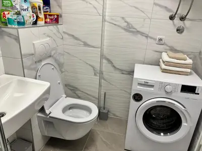 a bathroom with a toilet and a washing machine at Apartman Leo in Banja Luka
