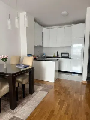 a kitchen with white cabinets and a table and chairs at Apartman Bonaca in Banja Luka