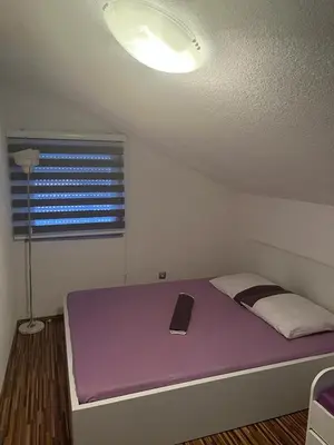 a room with a purple bed with a laptop on it at Holiday cottage-vikendica in Donji Podovi