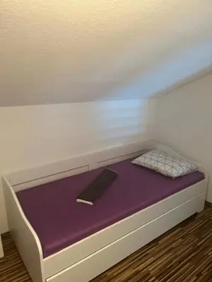 a bed with a purple mattress and a book on it at Holiday cottage-vikendica in Donji Podovi