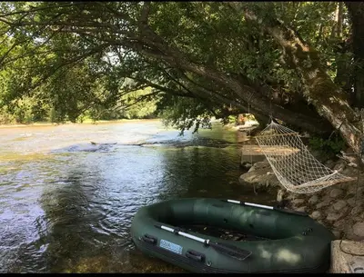 a raft and a hammock hanging from a tree over a river at Holiday cottage-vikendica in Donji Podovi