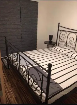 a bedroom with a black metal bed with a table at Holiday cottage-vikendica in Donji Podovi