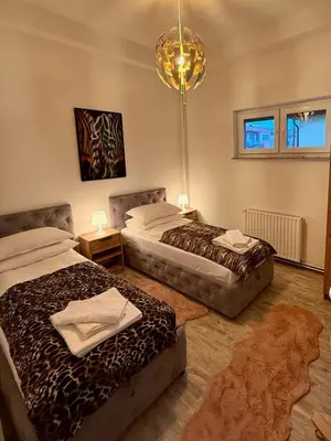 a bedroom with two beds and a chandelier at Apartman Tanzanija Bihać in Bihać