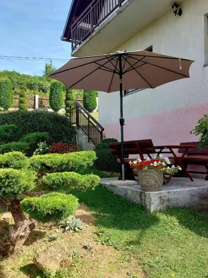 a table and bench with an umbrella in a garden at Apartman Vidikovac in Kupres
