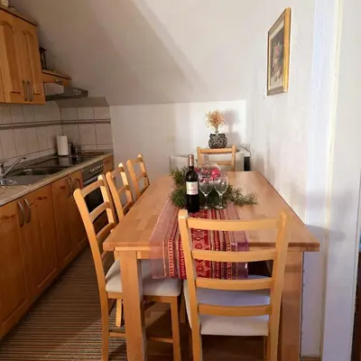 a kitchen with a wooden table with bottles of wine at Apartman Vidikovac in Kupres