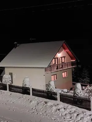 a house in the snow at night at Apartman Vidikovac in Kupres
