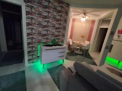 a living room with a brick wall and green lights at Apartman San in Bihać