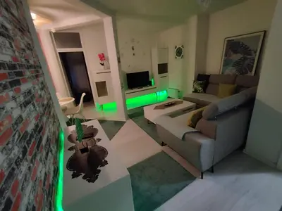 a living room with a couch and a television with green lights at Apartman San in Bihać