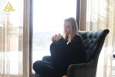 a woman sitting on a couch looking out a window at Weekend house - Vlašić in Vlasic