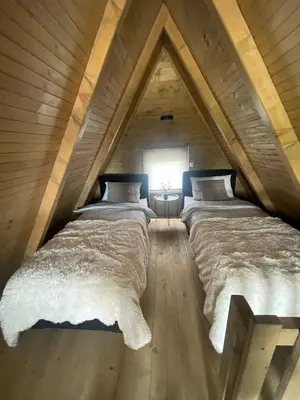 two beds in a room with a roof at Planinska kuća Marko in Vlasic