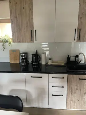 a kitchen with white cabinets and a black counter top at Planinska kuća Marko in Vlasic