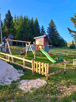 a playground with a wooden fence and a slide at Villa Encian in Travnik