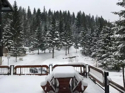 a table covered in snow on a balcony with trees at Apartman NANA Vlašić in Šišava
