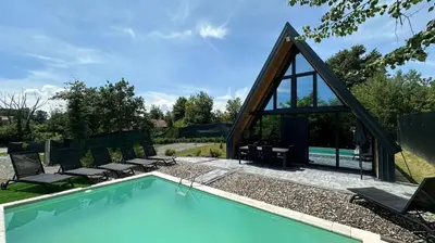 a swimming pool with chairs and a house at Wellness Borealis in Tuzla