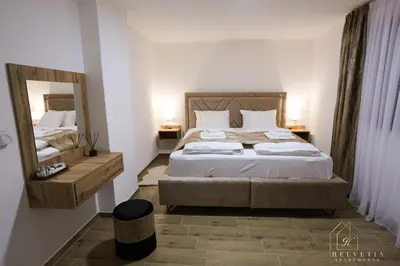 a bedroom with a large bed and a mirror at Helvetia Apartments in Jajce